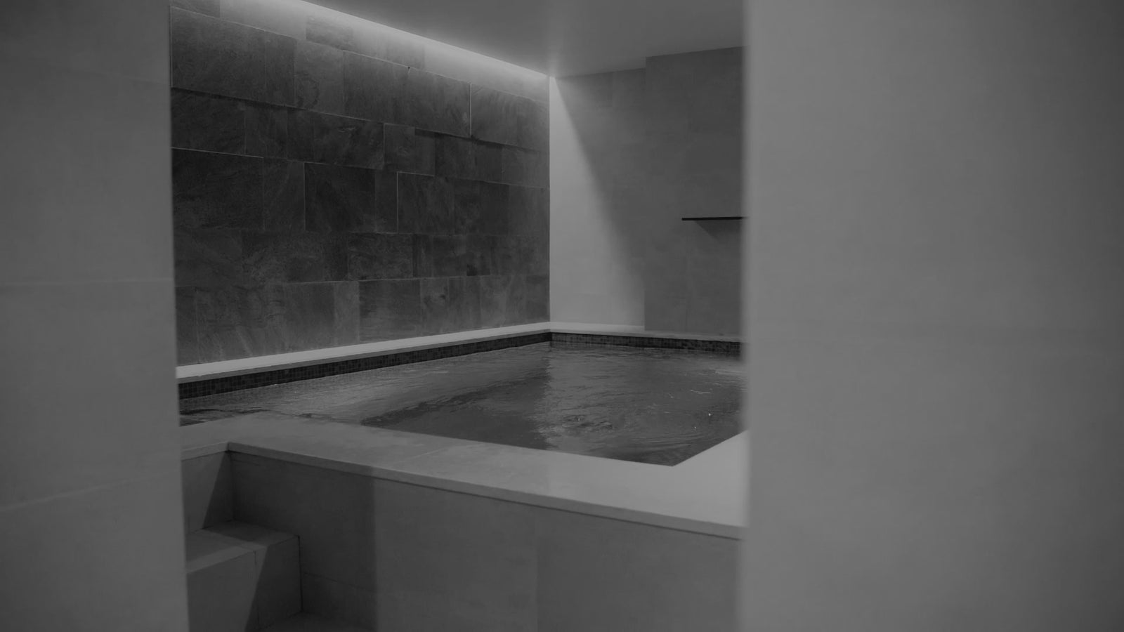 luxury spa bath with architectural lighting and waterfall